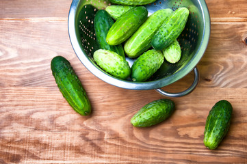 Mini cucumbers in colander on table