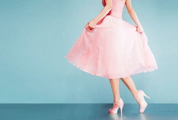 Romantic pink dress with pink shoes on vintage look blue background.