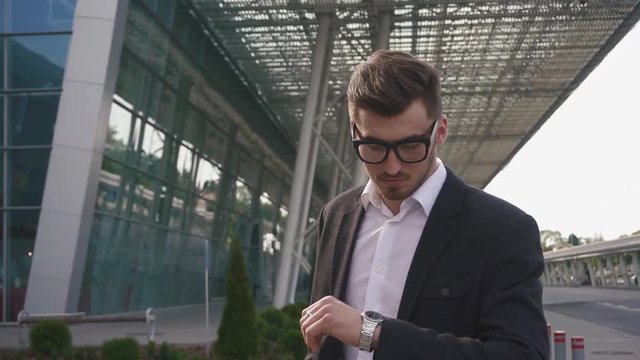 Close-up of handsome nervous businessman waiting for his retarded flight. Modern airport background