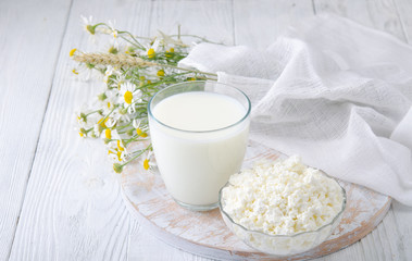 Fresh dairy products, Milk, cottage cheese, flowers on white wood background.