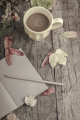 coffee mug and notebook on wooden table decorated with autumn leaves