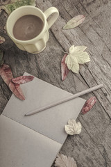 coffee mug and notebook on wooden table decorated with autumn leaves