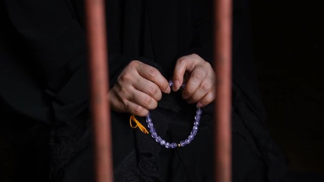Close up hand of muslim woman praying to god from jail.