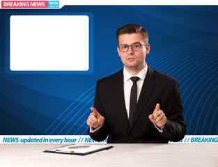 Television reporter telling breaking news at his studio desk wit