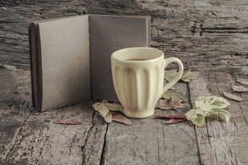 coffee mug and notebook on wooden table decorated with autumn leaves