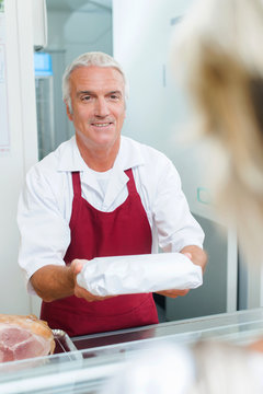 Butcher passing a package to a customer