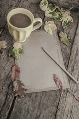 coffee mug and notebook on wooden table decorated with autumn leaves
