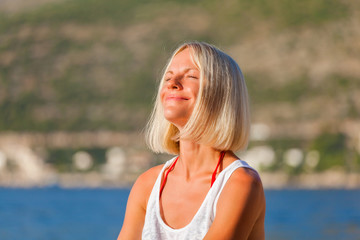 The blonde girl sunbathes on the beach in summer. Female traveler enjoying the sun. Summer vacation at sea. Dubrovnik. Croatia