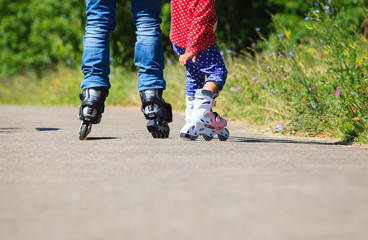 father teaching little daugther to roller skate in summer