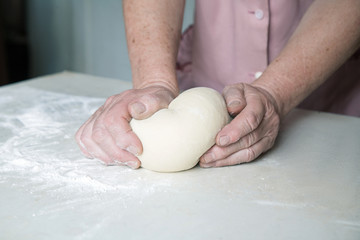 hands knead the dough on the table