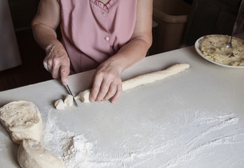 Hands of an old woman cut the dough