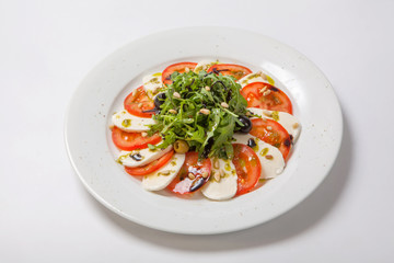 Caprese salad. Fresh salad with fresh juicy tomatoes with mozzarella cheese and fresh arugula tossed with balsamic vinegar and pine nuts