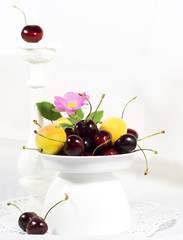 Ripe sweet cherry and apricots in a white vase for fruit     selective focus    design, effects,...
