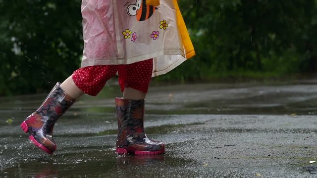 Kid in rain boots jumping chaotically in puddle