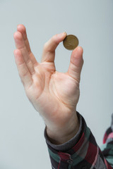man's hand holding a coin between two fingers, vertical