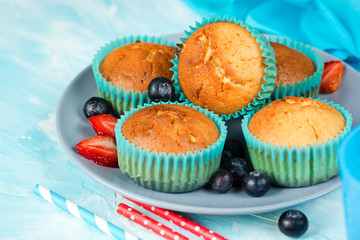 Classic muffins with fresh berries on the plate on a blue background