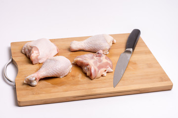 Raw chicken drumsticks on kitchen wooden board