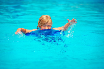Happy little boy playing in swimming pool on a hot summer day