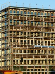 Neubau eines modernen Bürogebäude mit Baugerüst vor blauem Himmel im Sonnenschein am alten Hafen...