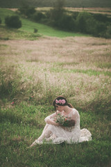 young   woman in white lacy dress on meadow