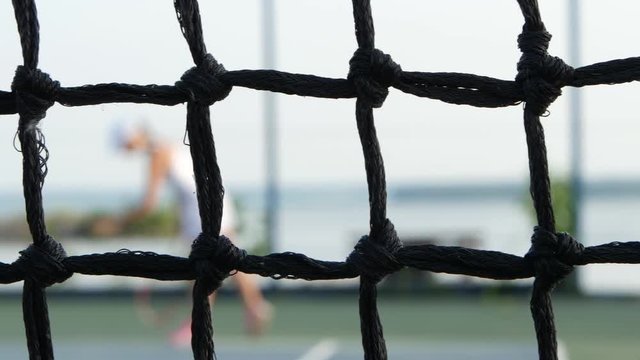 Tennis concept. Professional player expecting the tennis ball on court, net in front. Dolly shot