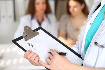 Close-up of a female doctor while filling up medical prescription
