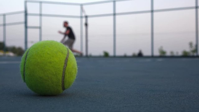 Tennis ball on the court. People are playing tennis outdoors