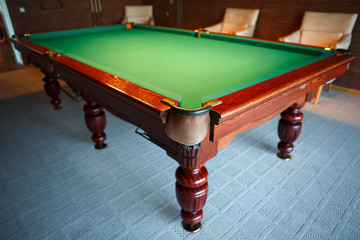 Pool table from natural slate covered with green cloth. Billiard room for the game. The movement of the balls with the cue - male fun.
