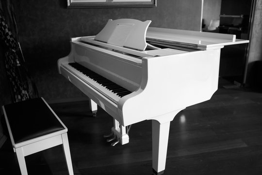 White piano in the black room. Musical keyboard instrument. Perfect equipment to extract the sounds. Classical music.