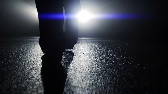 following man feet walking into light in dark night. spooky mystery scene