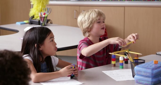 Two young kids use blocks in class, close-up, 