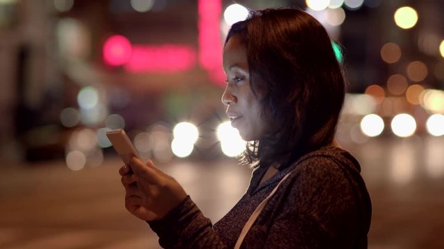 young black women standing on street in the city at night using tablet pc