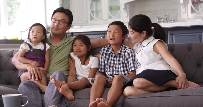 Family Sitting On Sofa At Home Watching TV 
