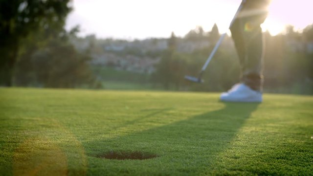 Slow Motion Shot Of Golfer Putting Ball Into Hole On Green