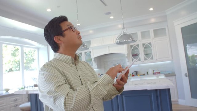 Man Using Digital Tablet To Control Lighting At Home