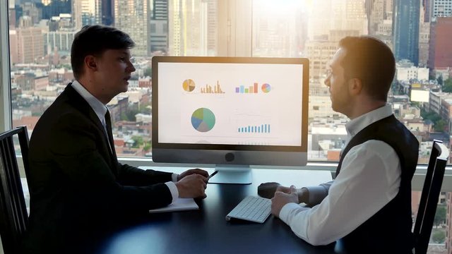 two businessman having a business meeting in modern high rise office building - Powered by Adobe