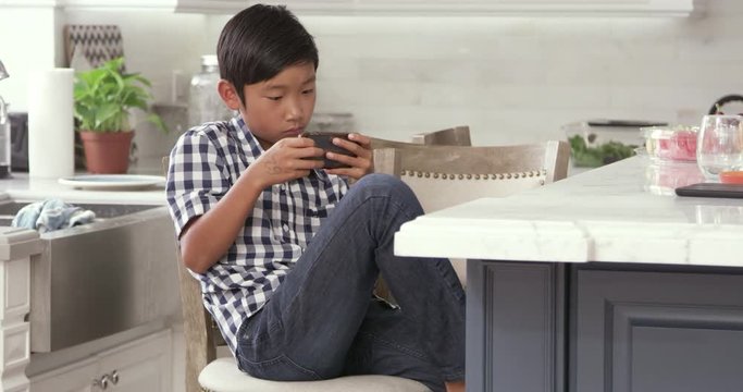 Young Asian Boy Playing Game On Mobile Device 