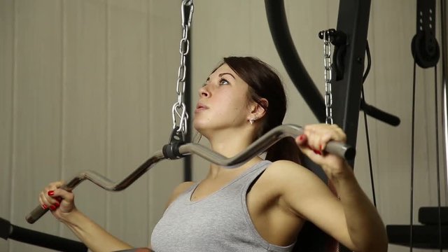 young woman goes in for sports, fitness at the gym. girl doing exercises on the simulator