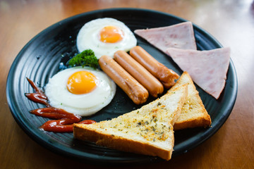 Breakfast with fried eggs, bacon, sausages and toasts.