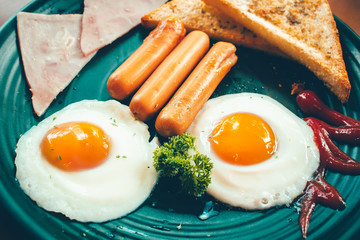 Breakfast with fried eggs, bacon, sausages and toasts.