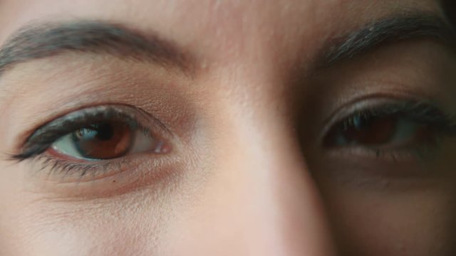 A woman&rsquo;s brown eyes blinking and creasing to smile, detail