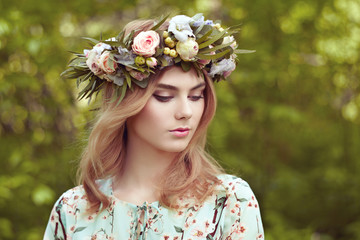 Naklejka premium Beautiful blonde woman with flower wreath on her head. Beauty girl with flowers hairstyle. Girl in a summer forest. Fashion photo