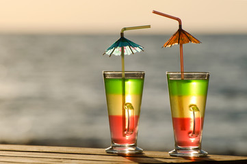 Two colorful cocktails in the morning sun on the sea background, close-up, empty space