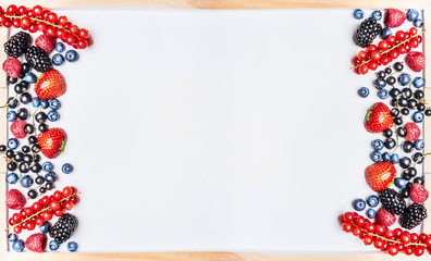 Various berries on white chalkboard background, top view, frame