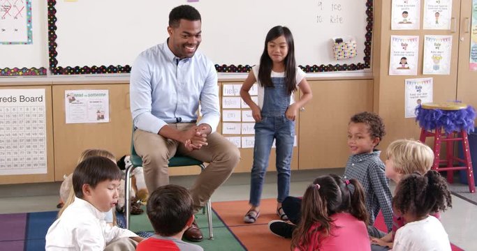 Asian schoolgirl standing with teacher in front of class
