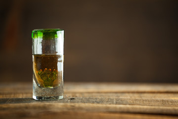 Gold tequila in glass on wood table. Selective Focus. Blurred background.