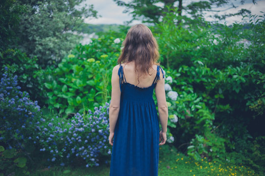 Young woman in blue dress by flowers