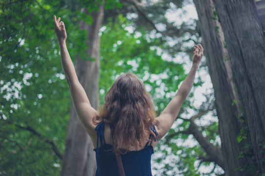 Woman raising her arms in the forest