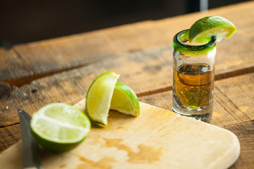 Shot glass of tequila with bottle. Selective focus. Blurred background.
