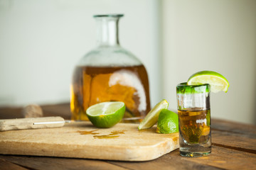 Shot glass of tequila with bottle. Selective focus. Blurred background.